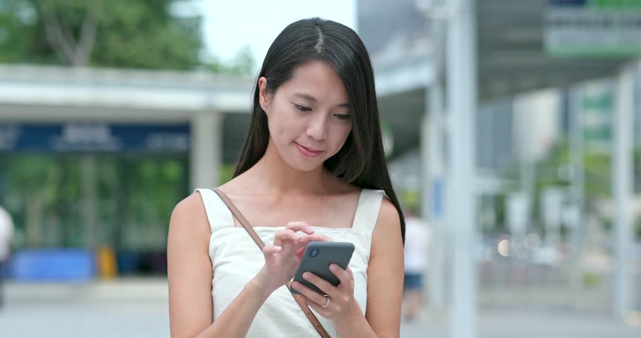 Asian Woman looks at the smart phone in city