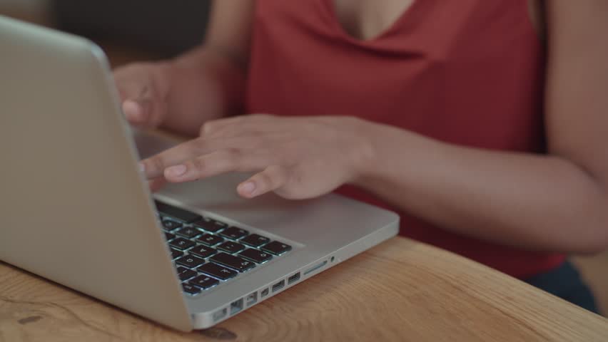 Young Afro American woman using laptop computer while sitting at table. | Shutterstock HD Video #1013058182