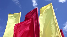Red and yellow flags fluttering in the wind against blue sky
