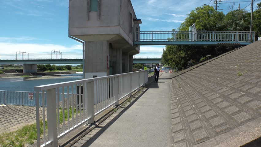 Young JAPANESE MAN WALKING at the riverside of Tama river in Tokyo.