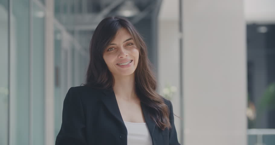 Portrait of young successful businesswoman standing in office hall looking at camera and smiling 4k | Shutterstock HD Video #1013074313