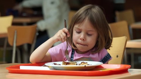 A funny child, a European-looking girl, does not like to eat chocolate. She refuses to eat a pancake drenched in chocolate.
