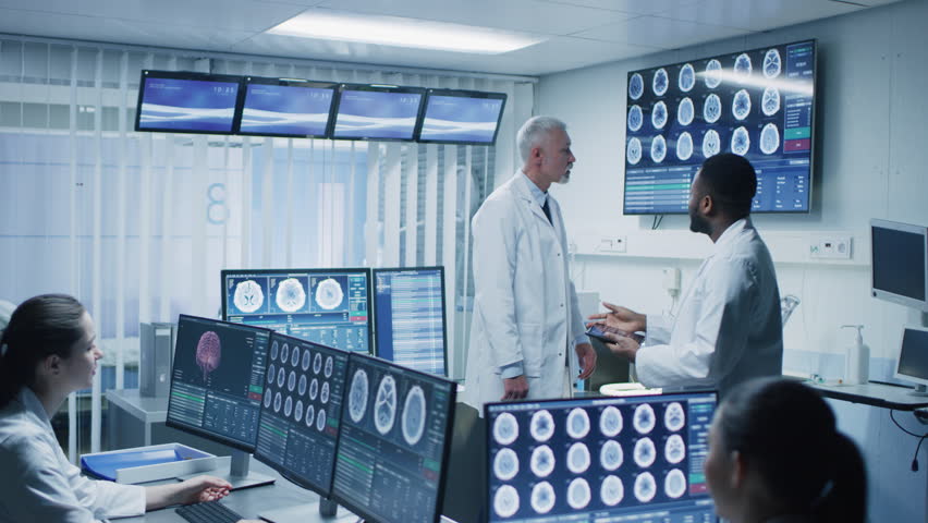 Team of Professional Scientists Work in the Brain Research Laboratory. Neurologists / Neuroscientists Surrounded by Monitors Showing CT, MRI Scans Having Working. Shot on RED EPIC-W 8K Helium Camera.