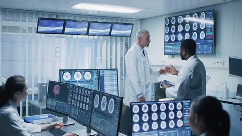 Team of Professional Scientists Work in the Brain Research Laboratory. Neurologists / Neuroscientists Surrounded by Monitors Showing CT, MRI Scans Having Working. Shot on RED EPIC-W 8K Helium Camera.