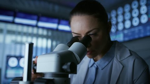Medical Research Scientist Looking under the Microscope in the Laboratory. Microbiologist, Chemist, Neurologist Solving Puzzles of the Mind and Mind and Brain