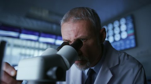 Senior Medical Research Scientist Looking under the Microscope in the Laboratory. Neurologist Solving Puzzles of the Mind and Brain. Shot on RED EPIC-W 8K Helium Cinema Camera.