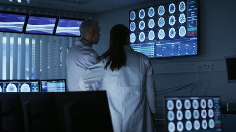 Two Medical Scientists / Neurologists, Talking and Working on a Personal Computer in Modern Laboratory. Research Scientists Making New Discoveries. Shot on RED EPIC-W 8K Helium Cinema Camera.