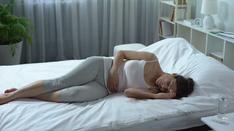 Young woman suffering from severe pain and cramp in lower abdomen, menstruation