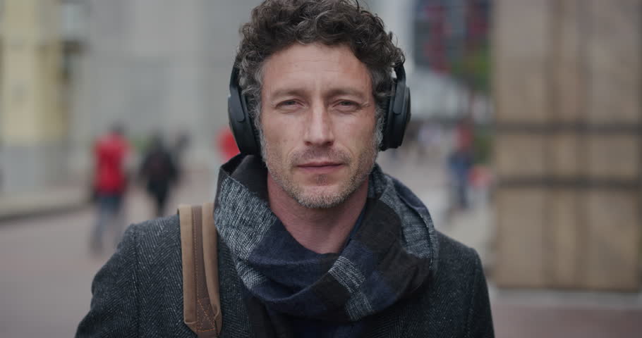 Portrait of attractive mature businessman taking off headphones, enjoying relaxed urban commuting lifestyle