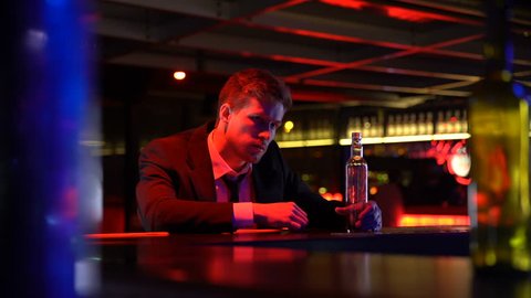 Drunk man alone stays late in bar, finishes whiskey bottle, suffering depression