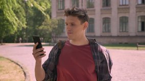 Young handsome man has a videocall in park in daytime in summer, communication concept
