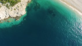 Aerial shot of a secluded private beach in the mediterranean sea. 4k drone video pan downward.