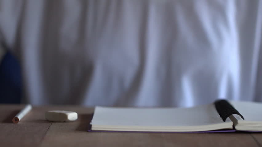 Women wearing white t-shirts are drinking coffee and writing a notebook on brown wooden table.