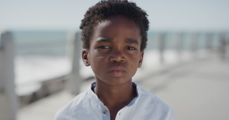 close up portrait happy african american boy smiling cheerful enjoying warm summer vacation on seaside beach waterfront slow motion Royalty-Free Stock Footage #1013096855