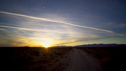 Time Lapse of a priceless golden sunset over a desert road with wispy clouds