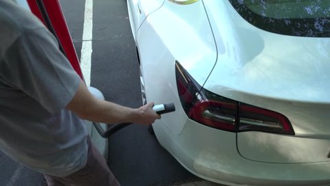 RALEIGH, NC - APRIL 30, 2018: Person charging a Tesla Model 3 at a Tesla Supercharger station in Raleigh, NC. Tesla motors develops network of the charging stations across the US and the world.