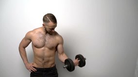 Slow motion video of a shirtless muscular man training biceps with dumbbell