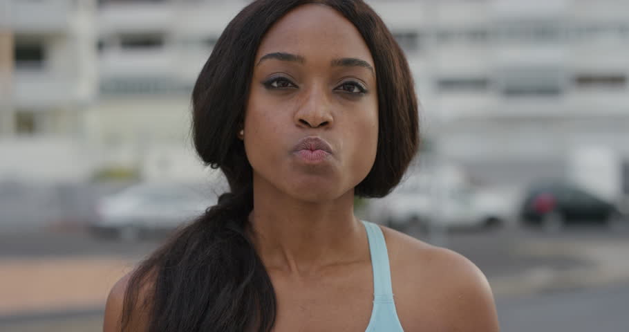 portrait playful young african american woman blowing bubblegum enjoying relaxed summer day outdoors slow motion