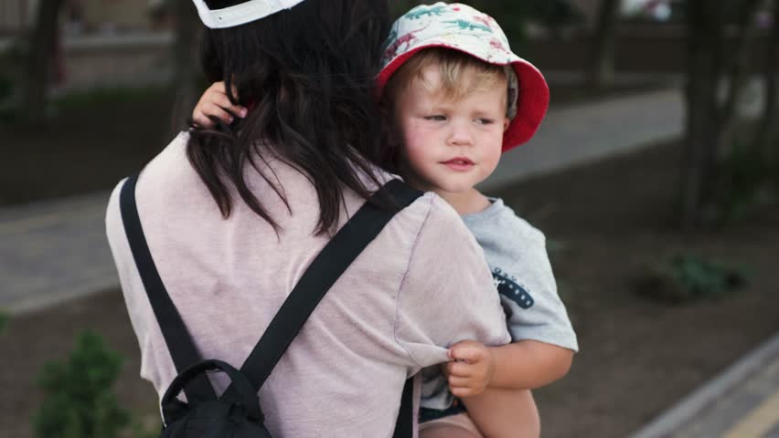 A loving mother carries her tired and bored child, patting him sympathetically