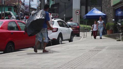 Medellin, Colombia - July 2, 2018: A homeless man walks away carrying a sack of recycled materials in Medellin
