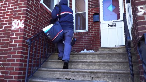 Philadelphia, Pennsylvania / United States - 03 23 2018: A United States Postal Service worker delivers mail on March 23, 2018, in North Philadelphia