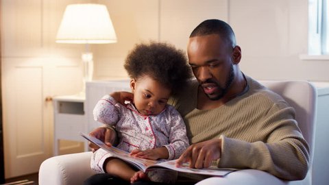Father Reading Book To Young Son At Home In Nursery