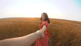 follow me. pretty portrait brunette girl goes with a man by the hand on nature field romance love. slow motion video lifestyle. girl and man walking call beckoning finger. follow me concept