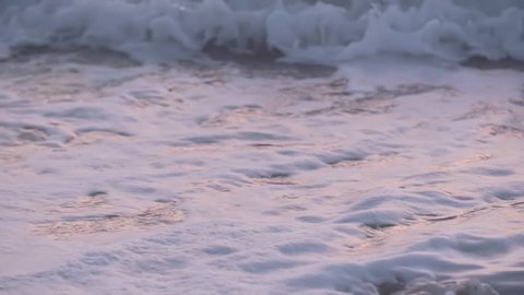 Slow motion ocean waves hitting the shore during a sunrise in Miami.