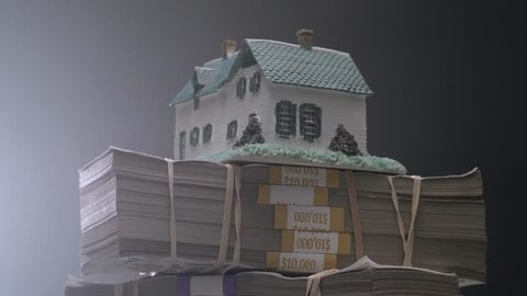 House on top of a large stack of money bills. Real estate mortgage concept shot.