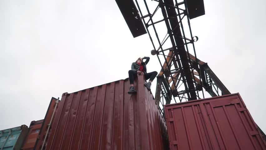 the girl sits on a freight container.