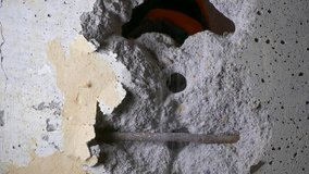 Ungraded: Worker hollows out a hole in reinforced concrete wall with hammer and chisel. 