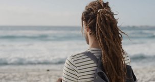 young tourist man taking photo on beach using smartphone camera technology of beautiful scenic ocean background caucasian male with dreadlocks rear view