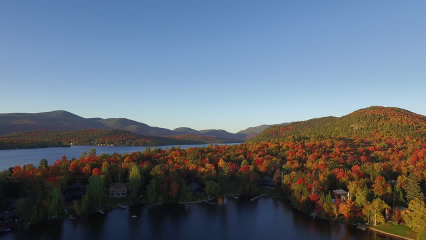 Low aerial pass over brilliant Adirondack fall foliage and blue lakes