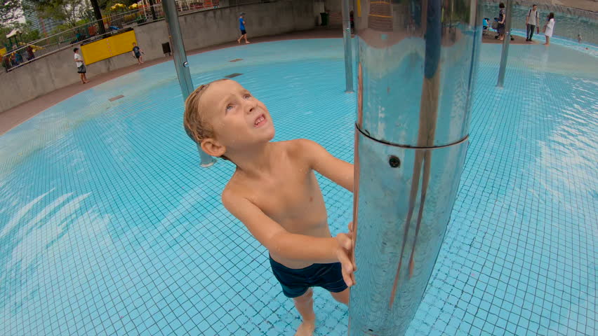Slowmotion shot of a little boy having fun in a pool in a park