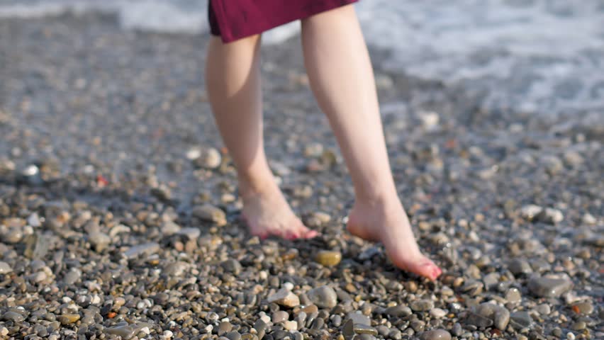 Woman bare feet walking along pebble beach and sea waves close up | Shutterstock HD Video #1013183792