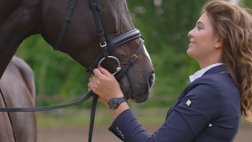 a young girl rider kisses a brown racehorse in her nose. cute video about the love of pets. Shooting at sunset on a warm summer day.