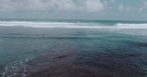 Aerial drone view of beautiful ocean waves with white water foam against cloudy sky - video in slow motion
