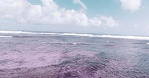 Aerial drone view of beautiful ocean waves with white water foam against cloudy sky - colored video in slow motion