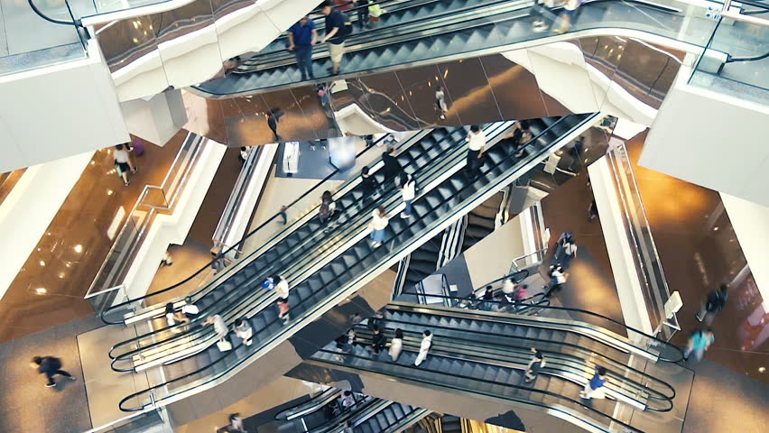 People on many fast moving Escalators In big modern shopping mall. Consumption concept. Time lapse