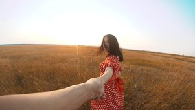 follow me. pretty portrait brunette girl goes with a man by the hand on nature field romance love. slow motion video. girl lifestyle and man walking call beckoning finger. follow me concept
