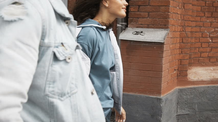 Slow motion, Young cheerful couple walking down the street holding hands, the girl takes her boyfriend