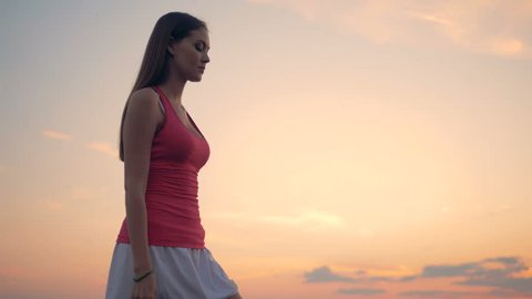 A girl practices yoga on a sunset background.