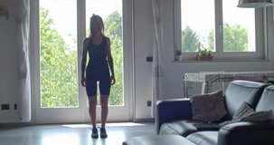 young tattooed woman doing jumping jacks exercise during home fitness sport workout .Living room domestic training. 4k slow motion video