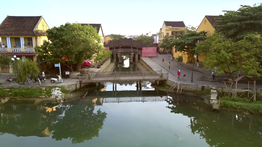 motion above footbridge along channel to famous Japanese bridge past two-storey houses in Hoian historial district