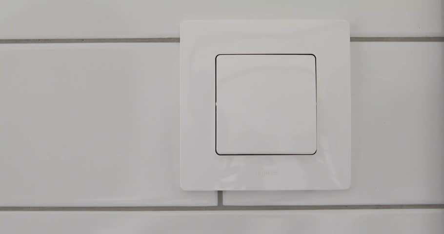 Female hand presses button of switch in bathroom close up. Hand with finger on light switch