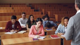 Tired mixed race student is sleeping during lecture at college, his classmates are waking him up, he is standing and talking to teacher, young people are laughing. - Powered by Shutterstock - Get 15% off with code: PIKWIZARD15