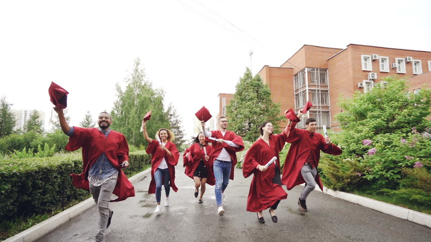 Slow motion of merry graduates running, holding diplomas and waving mortarboards enjoying freedom. Higher education, youth and happiness concept. | Shutterstock HD Video #1013212322