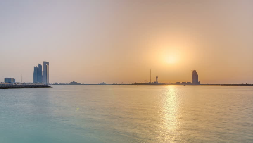 Sunset in Abu Dhabi over Marina Island timelapse, view from corniche. Orange warm light and reflection on water