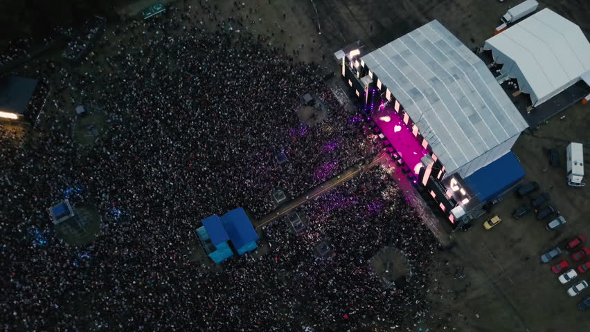 A large crowd of people at a music festival near the scene in the evening in the summer. Concert in the open air. Aerial view