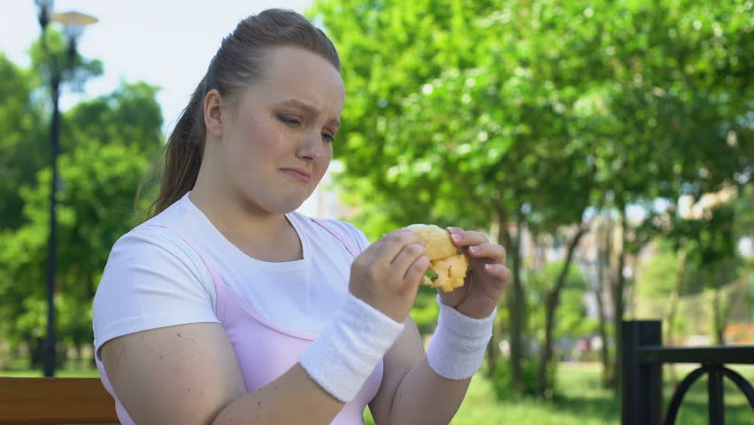 Cant resist. Teenager woman overweight. Temptations to eat.